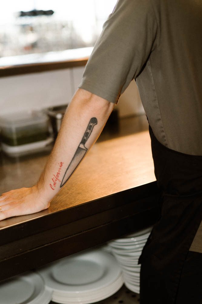 Foto van een man met een mes als tattoo op zijn onderarm